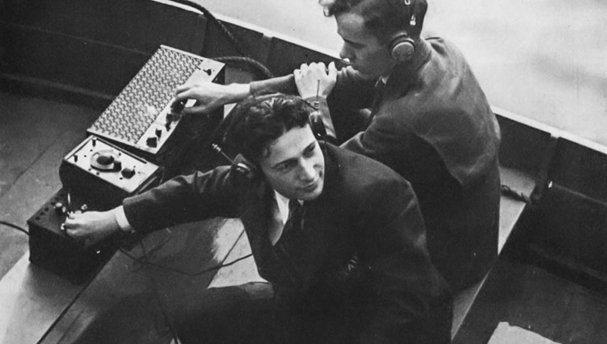 Archival image of two ment in a boat with a radio transmitter