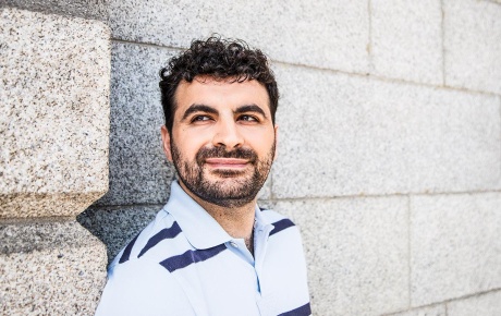 Close-up image of Aaron Gokaslan with a concrete brick wall behind him.