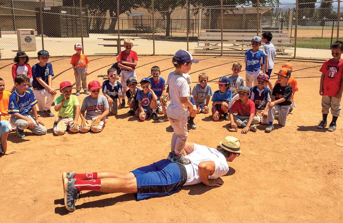 Image of James Lowe on the ground on a baseball field with players watching him.