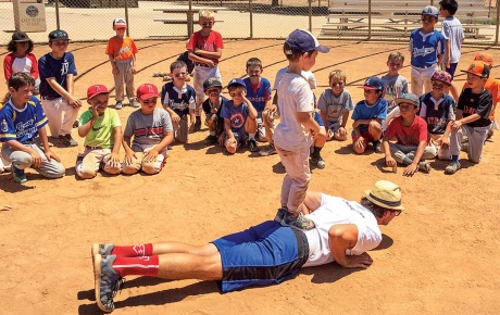 Image of James Lowe on the ground on a baseball field with players watching him.