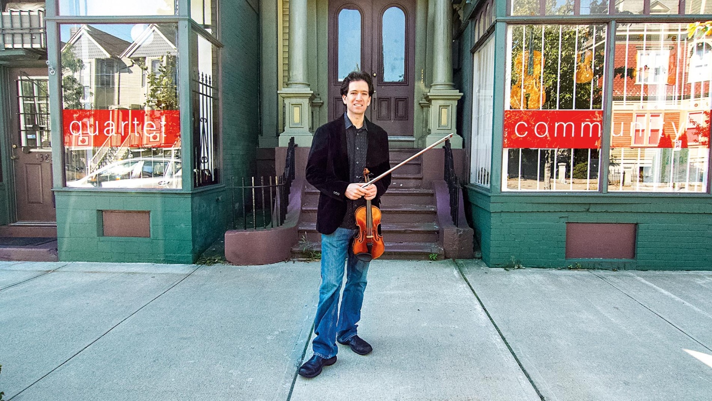 Image of Sebastian Ruth standing on the street with his violin