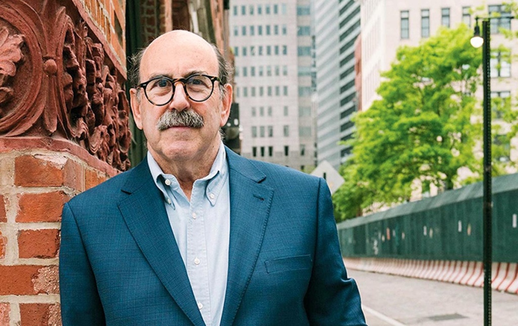 Image of Steve Cohen leaning against a brick pillar on the street