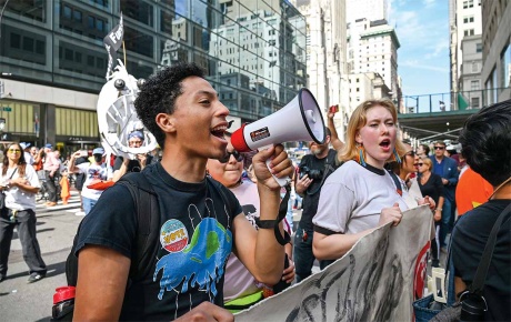 Image of individuals at a protest, one with a blowhorn.