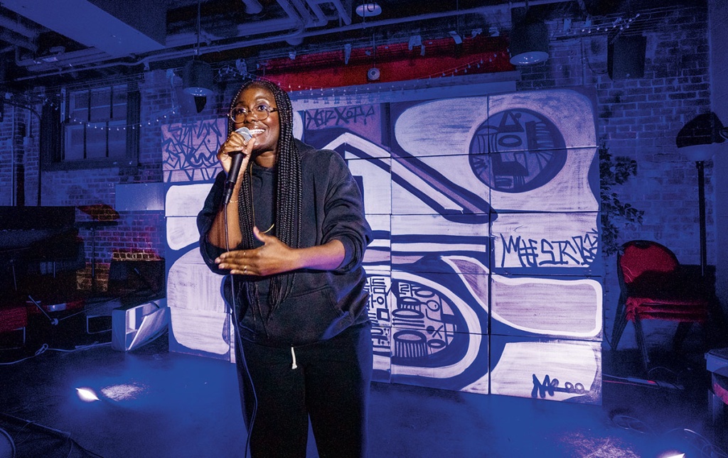 An image of Sammus on stage with a microphone