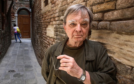 Image of Robert Coover leaning against a brick wall.