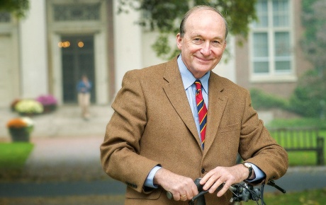 Image of Eric Widmer in a suit and tie smiling in front of a campus building